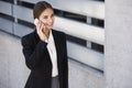 Beautiful young business woman is walking by a building while talking on the phone Royalty Free Stock Photo