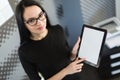 Beautiful young businesswoman in black dress and glasses hold paper folder and show tablet Royalty Free Stock Photo