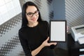 Beautiful young businesswoman in black dress and glasses hold paper folder and show tablet Royalty Free Stock Photo