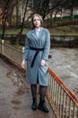 Beautiful young businesswoman in grey coat posing in Park autumn