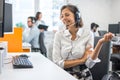 Beautiful young businesswoman with hands-free headset talking to a customer during online call in the office Royalty Free Stock Photo