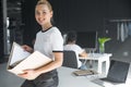 beautiful young businesswoman holding folder with documents and smiling at camera Royalty Free Stock Photo