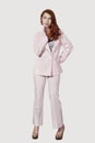 Beautiful young businesswoman in pink suit standing against gray background Royalty Free Stock Photo