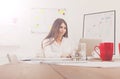 Beautiful young businesswoman sitting by office desk with laptop Royalty Free Stock Photo