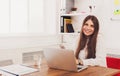 Beautiful young businesswoman sitting by office desk with laptop Royalty Free Stock Photo