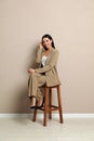 Beautiful young businesswoman sitting on stool near beige wall Royalty Free Stock Photo