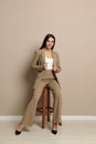 Beautiful young businesswoman sitting on stool near beige wall Royalty Free Stock Photo