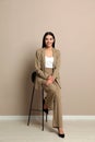 Beautiful young businesswoman sitting on stool near beige wall Royalty Free Stock Photo