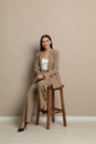 Beautiful young businesswoman sitting on stool near wall Royalty Free Stock Photo