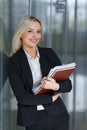 Beautiful young businesswoman smiling and standing with folder in the office. looking at camera Royalty Free Stock Photo