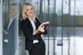 Beautiful young businesswoman smiling and standing with folder in the office. looking at camera. copy space. Royalty Free Stock Photo