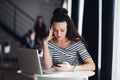 Beautiful young businesswoman using mobile phone while working with laptop in office, she is focused, trying to solve Royalty Free Stock Photo