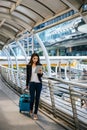 Beautiful young businesswoman walking outside public transportation station. Businesswoman traveler with suitcase on the way to Royalty Free Stock Photo