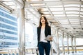 Beautiful young businesswoman walking outside public transportation station. Businesswoman traveler with suitcase on the way to Royalty Free Stock Photo