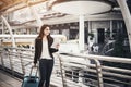 Beautiful young businesswoman walking outside public transportation station. Businesswoman traveler with suitcase on the way to Royalty Free Stock Photo