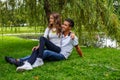 Beautiful young casual couple sitting on grss in a park. Royalty Free Stock Photo