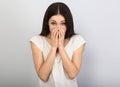 Beautiful young casual cute chuckle woman  covering the face the hands on blue background. Closeup portrait Royalty Free Stock Photo