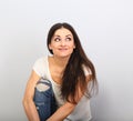 Beautiful young casual cute smiling woman on blue background looking up and thinking sitting in blue jeans. Closeup portrait Royalty Free Stock Photo