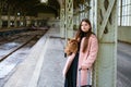 Beautiful young casual tourist woman with dog and suitcase waiting for train Royalty Free Stock Photo