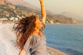 Beautiful young Caucasian brunette woman with long curly hair smiles and enjoys the sunset on the background of the Mediterranean Royalty Free Stock Photo