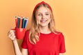 Beautiful young caucasian girl holding art colored pencils looking positive and happy standing and smiling with a confident smile Royalty Free Stock Photo