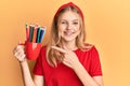 Beautiful young caucasian girl holding art colored pencils smiling happy pointing with hand and finger Royalty Free Stock Photo