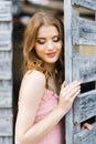 A beautiful young Caucasian girl with professional makeup with her eyes covered stands near a wooden gate in the city