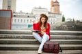 A beautiful, young Caucasian girl sitting on the street smile, the joy, sit with notebook and pen in Ruhi. In the red sweater, jea Royalty Free Stock Photo