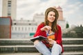 A beautiful, young Caucasian girl sitting on the street smile, the joy, sit with notebook and pen in Ruhi. In the red sweater, jea Royalty Free Stock Photo