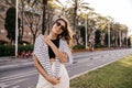 Beautiful young caucasian girl in sunglasses posing at camera walking outdoors. Royalty Free Stock Photo