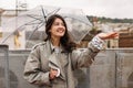 Beautiful young caucasian girl with umbrella puts her palm under rain standing outdoors.