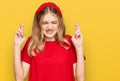 Beautiful young caucasian girl wearing casual red t shirt gesturing finger crossed smiling with hope and eyes closed Royalty Free Stock Photo