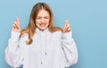 Beautiful young caucasian girl wearing casual sweatshirt gesturing finger crossed smiling with hope and eyes closed Royalty Free Stock Photo