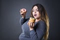 Beautiful young caucasian plus size model posing with donuts on a gray studio background Royalty Free Stock Photo