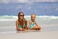 Beautiful young caucasian woman in blue bikini and little girl on the sandy beach. Summer family vacations, travel Royalty Free Stock Photo