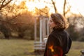 Beautiful young Caucasian woman enjoy sunny spring day, park cherry garden, romantic portrait, drinking coffee, lady in black coat Royalty Free Stock Photo