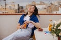 Beautiful young caucasian woman enjoys freshly squeezed orange juice sitting outdoors. Royalty Free Stock Photo