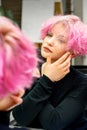 The beautiful young caucasian woman with a new short pink hairstyle looking at her reflection in the mirror checking Royalty Free Stock Photo