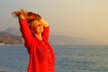 A beautiful young Caucasian woman in a pink blouse with red hair smiles and enjoys the sunset against the background of the Medite Royalty Free Stock Photo