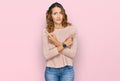Beautiful young caucasian woman wearing casual sweater pointing to both sides with fingers, different direction disagree Royalty Free Stock Photo