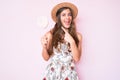 Beautiful young caucasian woman wearing summer hat and lollipop smiling happy pointing with hand and finger Royalty Free Stock Photo