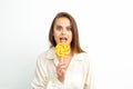 Beautiful young caucasian woman wearing a white shirt licking a lollipop on a white background. Royalty Free Stock Photo