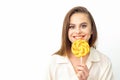 Beautiful young caucasian woman wearing a white shirt licking a lollipop on a white background. Royalty Free Stock Photo