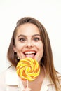 Beautiful young caucasian woman wearing a white shirt licking a lollipop on a white background. Royalty Free Stock Photo