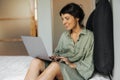 Beautiful young caucasian woman working at her laptop on white bed in room. Royalty Free Stock Photo