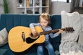 Beautiful young charming little girl smiling while playing classic guitar at home. Royalty Free Stock Photo