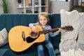 Beautiful young charming little girl smiling while playing classic guitar at home. Royalty Free Stock Photo