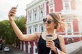 Beautiful young cheerful dark-haired hispanic girl in sunglasses an black dress smiling with teeth, taking selphie in Royalty Free Stock Photo