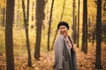 Beautiful young cheerful european woman wearing beret and coat walking in autumn forest Royalty Free Stock Photo