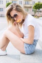 Beautiful young cheerful happy girl eating ice cream , smiling in shorts and a white T-shirt on the area on a bright sunny day